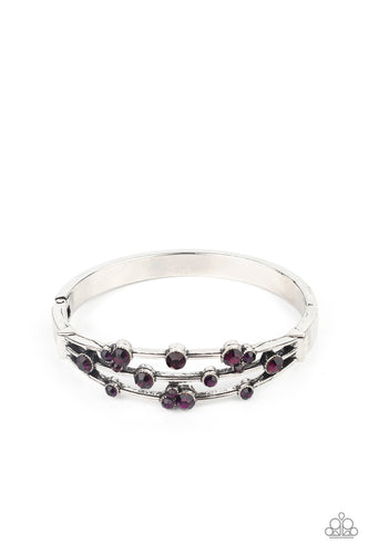 A smattering of glittery purple rhinestones adorn three silver bars that coalesce into a versatile silver cuff-like bangle around the wrist. Features a hinged closure.