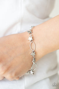 Dainty silver stars and airy silver ovals delicately link around the wrist, creating a stellar 4th of July display. Features an adjustable clasp closure.