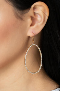 Dotted in dainty white rhinestones, an asymmetrical oval gold frame swings from the ear for a sassy look. Earring attaches to a standard fishhook fitting. 