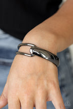 Load image into Gallery viewer, A flat gunmetal bar and airy gunmetal frame delicately overlap around the wrist, creating an oversized cuff-like bangle for a modern twist. Features a hinged closure.
