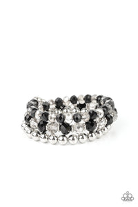 Sections of shiny silver beads and an alternating pattern of smoky and glittery black rhinestone gems gradually increase in size along a coiled wire, creating a jaw-dropping infinity wrap bracelet around the wrist.