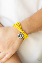 Load image into Gallery viewer, A shiny silver floral charm glides along stretchy strands of mismatched yellow seed beads, creating vibrant layers around the wrist. 
