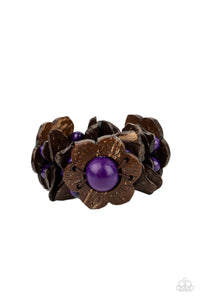 Distressed brown wooden pieces and round purple wooden beads join colorful wooden floral accents along stretchy bands around the wrist, creating a tropical inspired centerpiece. 