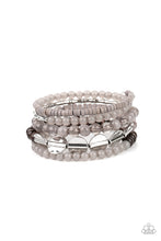 Load image into Gallery viewer, Mismatched sections of glassy and opaque gray beads join silver discs, brown wooden beads, and gray disc-like beads along a coiled wire, creating an earthy infinity wrap bracelet around the wrist.
