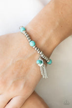 Load image into Gallery viewer, An earthy collection of hammered silver beads and round turquoise stones are threaded along a stretchy band around the wrist. A dainty silver tassel, hammered silver disc, and a turquoise stone swing from the seasonal display, adding playful movement to the whimsy look.
