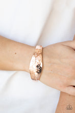 Load image into Gallery viewer, The front of a thick rose gold bangle-like bracelet is stamped in a leafy floral pattern, creating a whimsy centerpiece around the wrist. Features a hinged closure.
