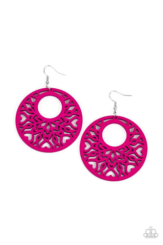 Painted in a vibrant pink, an airy circular wooden frame features a cut-out heart motif reminiscent of bohemian designs creating a free-spirited allure. Earring attaches to a standard fishhook fitting.