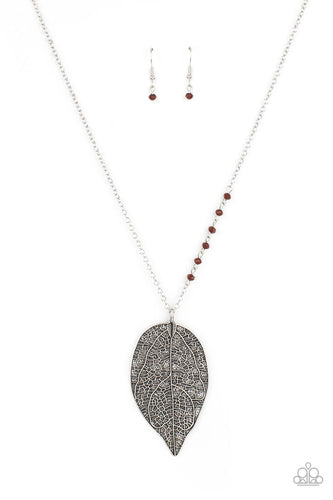 One side of a lengthened silver chain is dotted in dainty brown crystal-like beads as it gives way to an oversized leaf pendant embossed in lifelike textures for a seasonal finish. Features an adjustable clasp closure. 