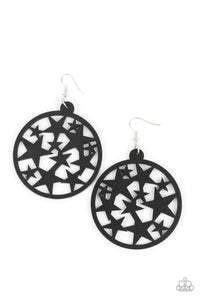 An oversized round black wooden frame is filled with a cosmos of cut-out black stars creating a whimsical statement. Earring attaches to a standard fishhook fitting.