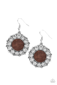 Layers of shiny silver petals bloom from a flat brown wooden center, creating a whimsically rustic display. Earring attaches to a standard fishhook fitting.