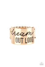 Load image into Gallery viewer, The front of a thick gold band is stamped in the phrase, &quot;Dream out loud,&quot; creating an inspirational centerpiece across the finger. Features a stretchy band for a flexible fit.
