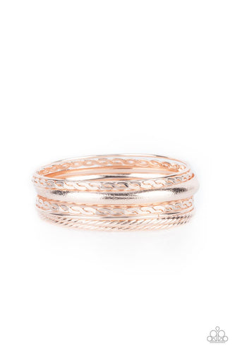 Featuring a polished finish, a mismatched collection of textured, braided, hammered, and plain rose gold bangles stack across the wrist for a classic metallic look. 