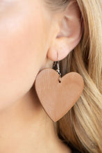 Load image into Gallery viewer, A tan leather heart frame swings from the ear for a flirtatiously neutral pop of color. Earring attaches to a standard fishhook fitting.
