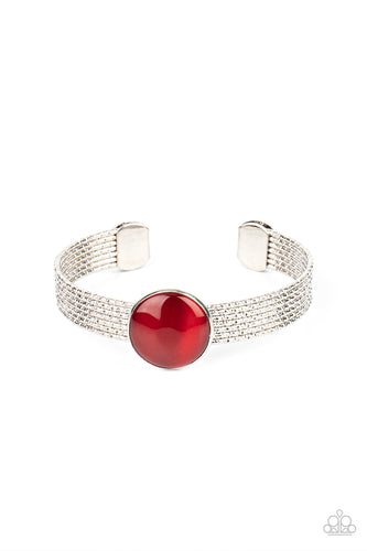 A glassy red cat's eye stone frame sits atop a layered silver cuff that is etched in shimmery textures, creating a glittery centerpiece. 