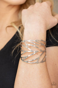 Hammered in rustic details, an airy silver feather wraps around the wrist, creating a seasonal cuff.