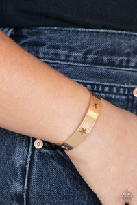 Airy gold stars are cutout along a classic gold cuff, creating a stellar centerpiece around the wrist.