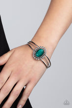 Load image into Gallery viewer, Bordered in glitzy rings of glittery white rhinestones and shiny silver studs, a faceted Leprechaun gem adorns the center of an ornately layered silver cuff for a flowery fashion.
