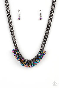 Flecked in oil spill iridescence, a faceted collection of metallic beads cluster along the center of a chunky gunmetal curb chain, creating a stellar fringe below the collar. Features an adjustable clasp closure.  Sold as one individual necklace. Includes one pair of matching earrings.