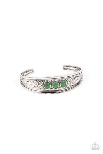 A trio of oval jade stones are pressed into the center of an ornate silver cuff that is embossed in leafy floral details, creating a seasonal pop of color around the wrist.
