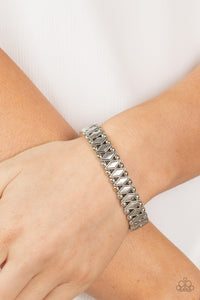 Brushed in an antiqued shimmer, pairs of dainty silver beads flank diamond shaped silver beads along stretchy bands around the wrist for a rustic fashion.