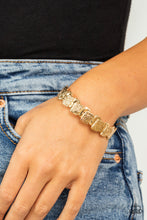 Load image into Gallery viewer, Featuring hammered and linear etched patterns, stacks of shiny gold rectangular frames are threaded along stretchy bands around the wrist for an urban look.
