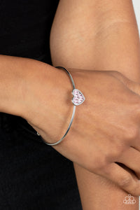 Brimming with dainty emerald-cut pink rhinestones, a simple silver heart frame sits atop a classic silver bar curved into a simple cuff bracelet for a whimsical display across the wrist. 