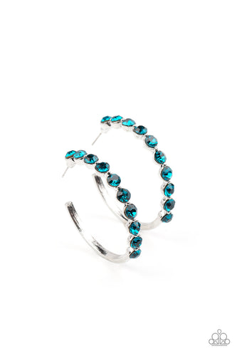 The front of a bold silver hoop is encrusted in glittery blue rhinestones, creating a glamorous pop of sparkle. Earring attaches to a standard post fitting. Hoop measures approximately 1 3/4