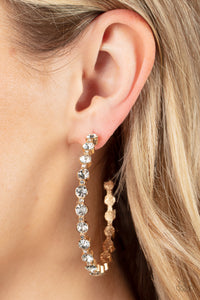 Encased in sleek gold fittings, a glamorous collection of glittery white rhinestones delicately coalesce into an oversized hoop for a sparkly statement. Earring attaches to a standard post fitting. Hoop measures approximately 2 1/2" in diameter. 