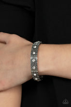 Load image into Gallery viewer, Dotted with dainty white rhinestone centers, floral filigree embossed silver frames are threaded along stretchy bands around the wrist for a romantic pop of color.
