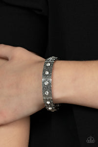 Dotted with dainty white rhinestone centers, floral filigree embossed silver frames are threaded along stretchy bands around the wrist for a romantic pop of color.