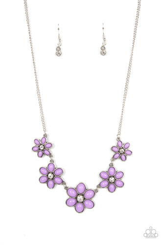 Dotted with dainty white rhinestone centers, a flirtatious assortment of purple beaded flowers gradually increase in size as they link below the collar for a playful pop of color. Features an adjustable clasp closure.