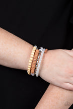 Load image into Gallery viewer, Mismatched sections of glassy and opaque white beads join silver discs, brown wooden beads, and brown disc-like beads along a coiled wire, creating an earthy infinity wrap bracelet around the wrist. 
