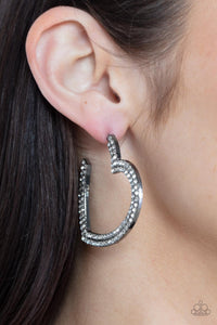 Tow rows of blinding white rhinestones are encrusted along the front of a heart shaped gunmetal hoop, creating a heart-stopping sparkle. Hoop measures approximately 2" in diameter. Earring attaches to a standard post fitting.