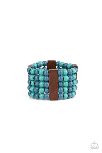 Colorful layers of blue and turquoise wooden beads are threaded along stretchy bands between dark brown wooden bars creating stacks of subtle bliss around the wrist. 