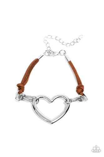 Strands of brown suede knot around sections of chunky silver chains that have been adorned in an oversized silver heart frame, resulting in a flirtatious display around the wrist. Features an adjustable clasp closure.