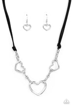 Load image into Gallery viewer, Strands of black suede knot around sections of chunky silver chains that have been adorned in oversized silver heart frames, resulting in a flirtatious display below the collar. Features an adjustable clasp closure.
