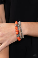 Load image into Gallery viewer, A mismatched collection of silver discs, silver cubes, bubbly orange acrylic, and silver pebble-like beads are threaded along stretchy bands around the wrist, creating vivacious layers
