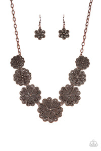 Featuring metallic wicker-like patterns, stacks of teardrop and heart shaped filigree-filled copper petals delicately link into a decorative row of flowers. The floral frames gradually increase in size as they move towards the center, creating a vintage inspired display below the collar. Features an adjustable clasp closure. 