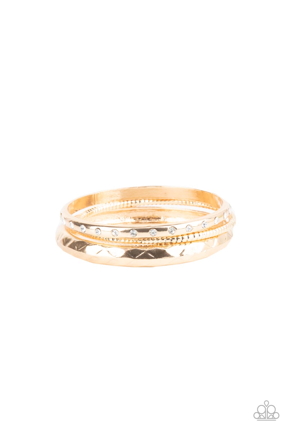 A thick gold bangle that is embossed and faceted in an edgy geometric pattern joins a mismatched pair of white rhinestone encrusted and diamond cut gold bangles that glide along the wrist, displaying a gritty pop of shimmer. 