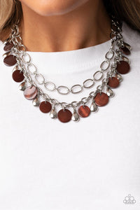  A pair of mismatched chunky silver chains layer below the collar. Shiny silver teardrop beads and brown shell-like discs dance from the bottom of the lowermost chain, creating a tropical inspired fringe. Features an adjustable clasp closure.