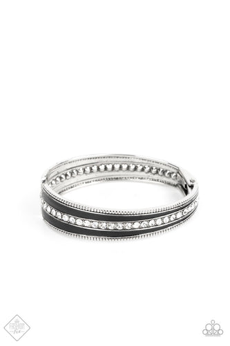 Two elongated flared frames painted in a glossy black finish connect at their tapered ends to a hinge. A row of rhinestones runs down the center of each frame, adding blinding sparkle to the piece, as the subtle studded borders of the frames add a hint of edge. Features a hinged closure.  Sold as one individual bracelet.