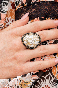 An earthy brown and white marbled stone is pressed into a rustic brass frame adorned with rope-like texture, creating a rustic centerpiece atop the finger. Features a stretchy band for a flexible fit.  Sold as one individual ring.