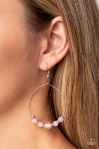 Infused with dainty silver accents, opaque and glassy pink beads glide along a wire hoop for an ethereal pop of color. Earring attaches to a standard fishhook fitting. 