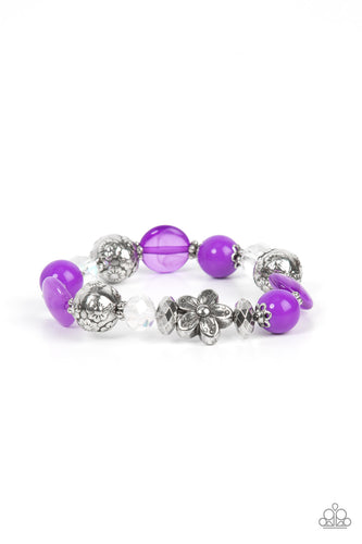 An enchanting assortment of silver floral beads and studded silver rings join an opaque, glassy, and iridescent assortment of purple and white beads along a stretchy band around the wrist for a whimsical pop of color.