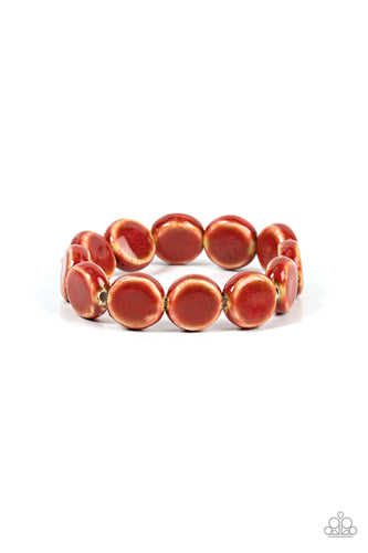 Glazed in a distressed red finish, an oversized collection of ceramic beads are threaded along a stretchy band around the wrist for a rustic fashion. 