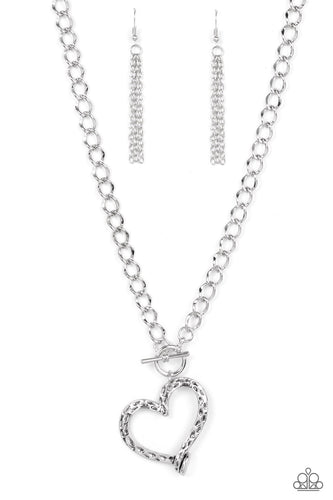 A hammered silver heart frame gently twists from a toggle closure at the bottom of a chunky silver chain, resulting in a romantically rustic pendant. Features a toggle closure.