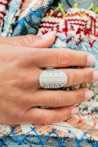 An oval shaped disc is divided down the center by a smooth band of silver. Silver studs and embellished texture are mirrored on either side of the divide as the band curves across the finger for an understated yet timeless finish. Features a stretchy band for a flexible fit.  Sold as one individual ring.  Fashion Fix