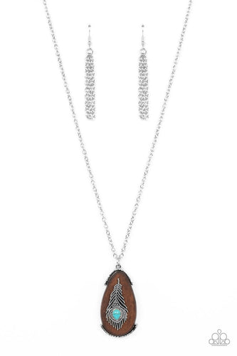 A teardrop turquoise stone adorns a studded silver feather that embellishes an oversized wooden pendant at the bottom of an extended silver chain, resulting in a whimsically rustic pendant. Features an adjustable clasp closure.