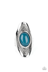 An oversized, glassy, blue bead is pressed into the center of a dramatically elongated silver frame. Triangular patterns are etched into the frame as it folds around the finger, resulting in an ethereal pop of color atop the finger. Features a stretchy band for a flexible fit.