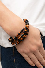 Load image into Gallery viewer, Stretchy strands of dainty brown and black wooden beads attach to a single strand of oversized brown and black wooden beads, resulting in colorful layers around the wrist.
